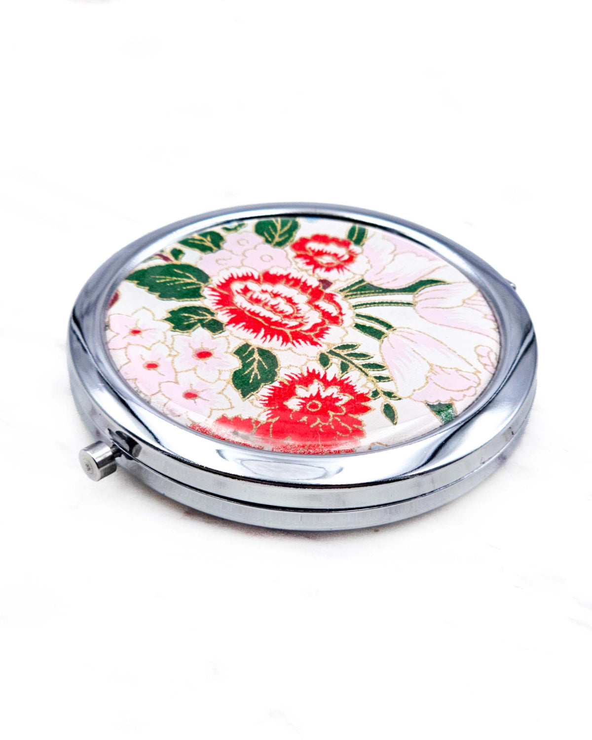 Round silver metal compact mirror featuring red and white peonies, soft pink and white flowers, and dark green leaves on a white background with metallic gold details.