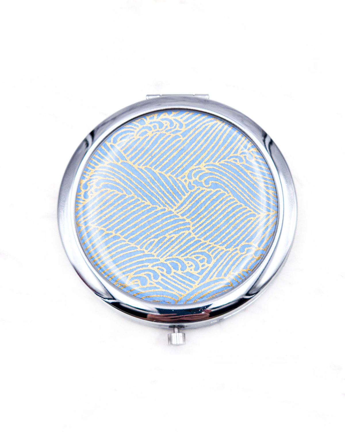 Round silver metal compact mirror featuring small metallic gold waves (aranami) on a light blue background.