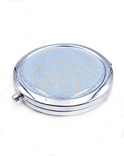 Round silver metal compact mirror featuring small metallic gold waves (aranami) on a light blue background.