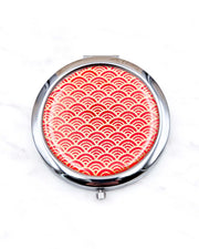 Round silver metal compact mirror featuring a small traditional red and metallic gold seigaiha (wave crests) pattern.