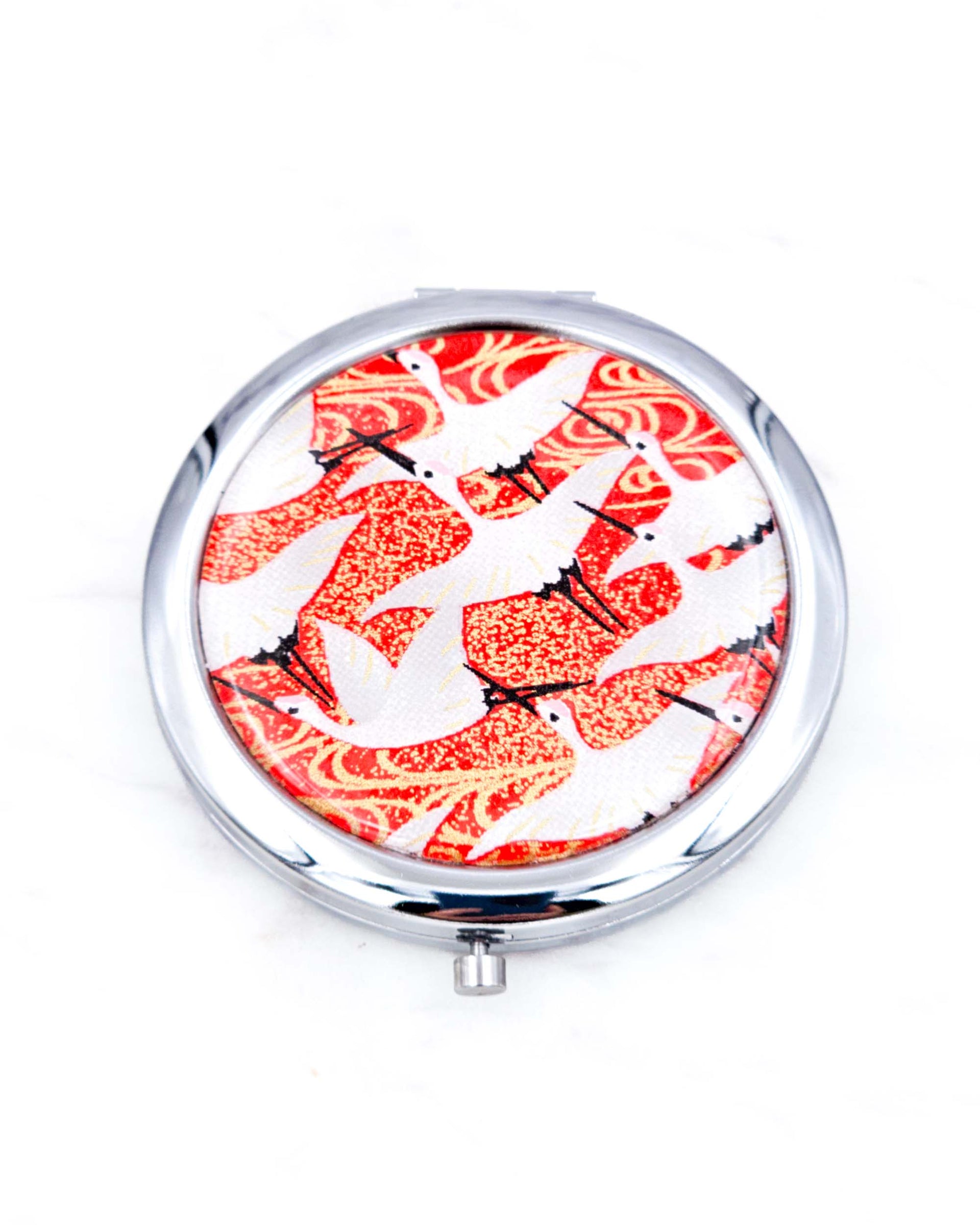 Silver metal compact mirror featuring flying white cranes on a red background with metallic gold accents
