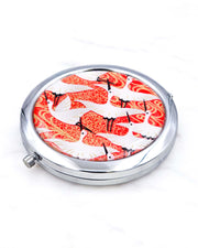 Silver metal compact mirror featuring flying white cranes on a red background with metallic gold accents