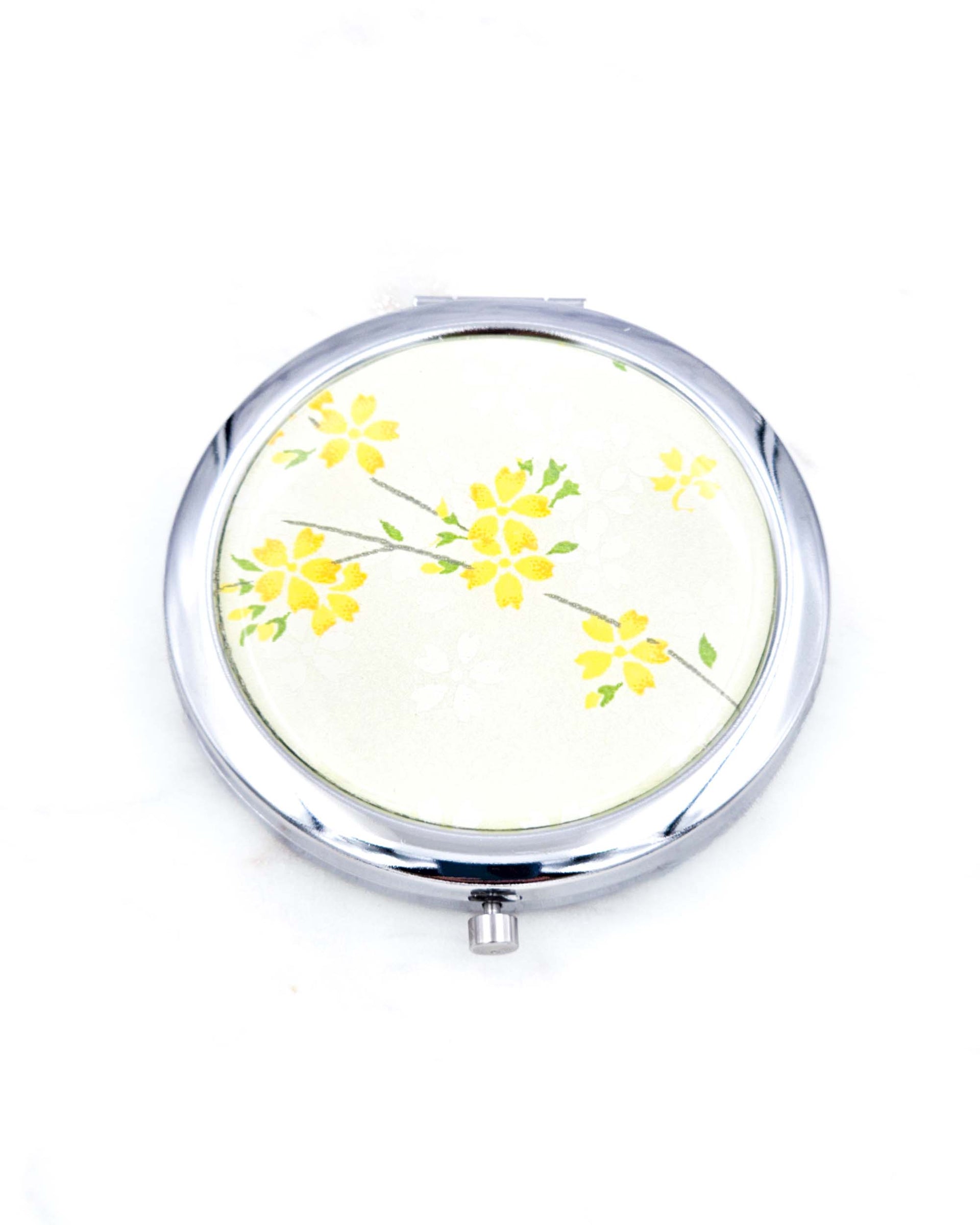 Silver metal compact mirror featuring yellow cherry blossoms on pearlescent yellow background.