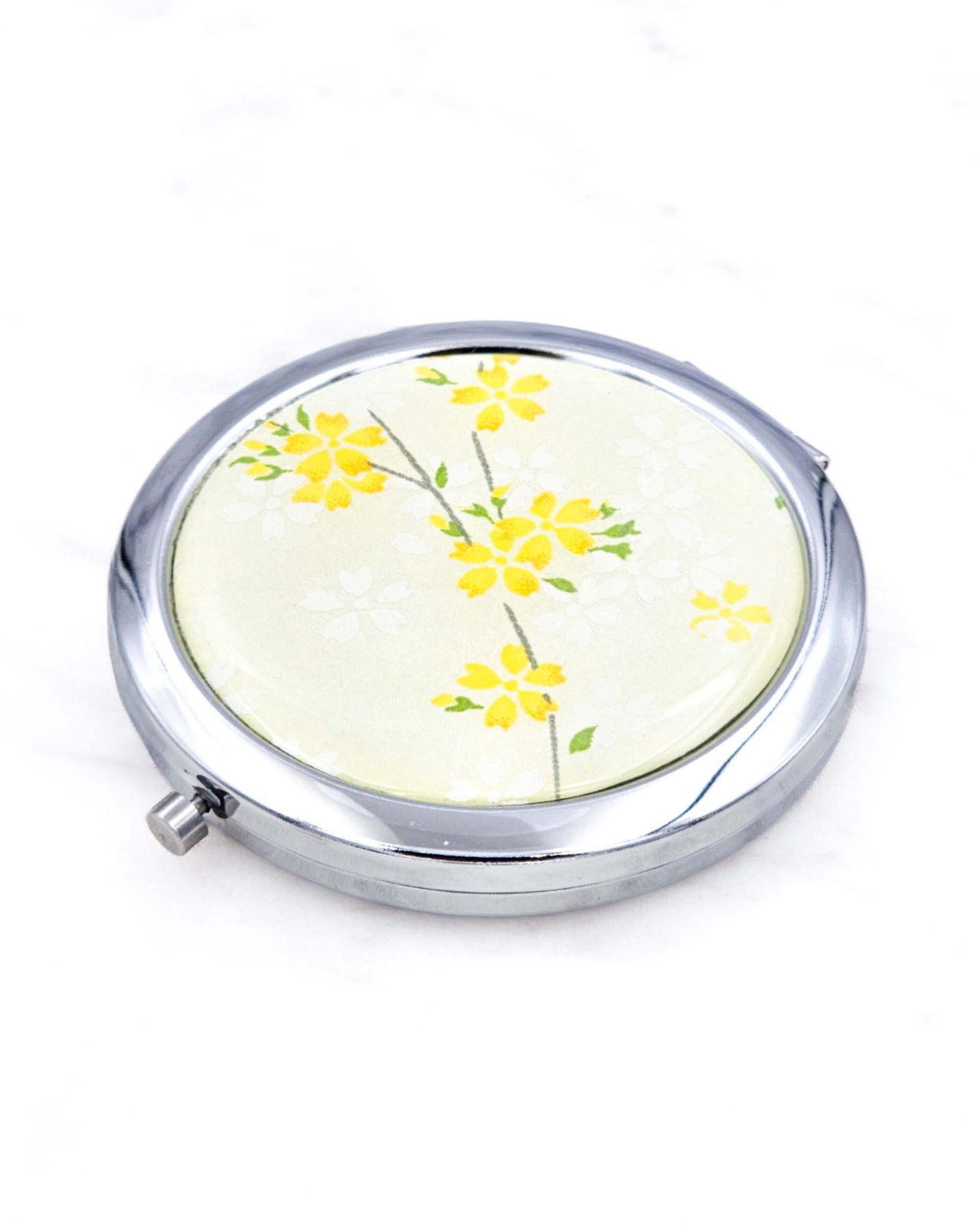 Silver metal compact mirror featuring yellow cherry blossoms on pearlescent yellow background.