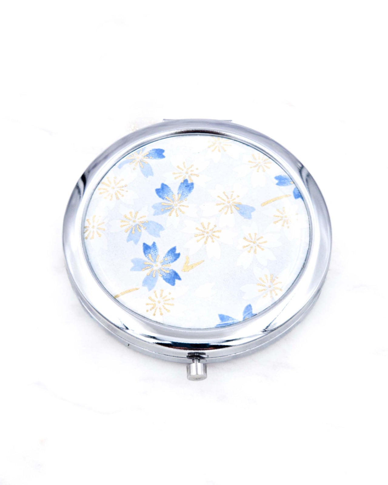 Silver metal compact mirror featuring white and blue cherry blossoms on a light white and blue background with metallic gold accents.