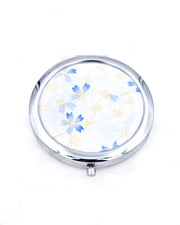 Silver metal compact mirror featuring white and blue cherry blossoms on a light white and blue background with metallic gold accents.
