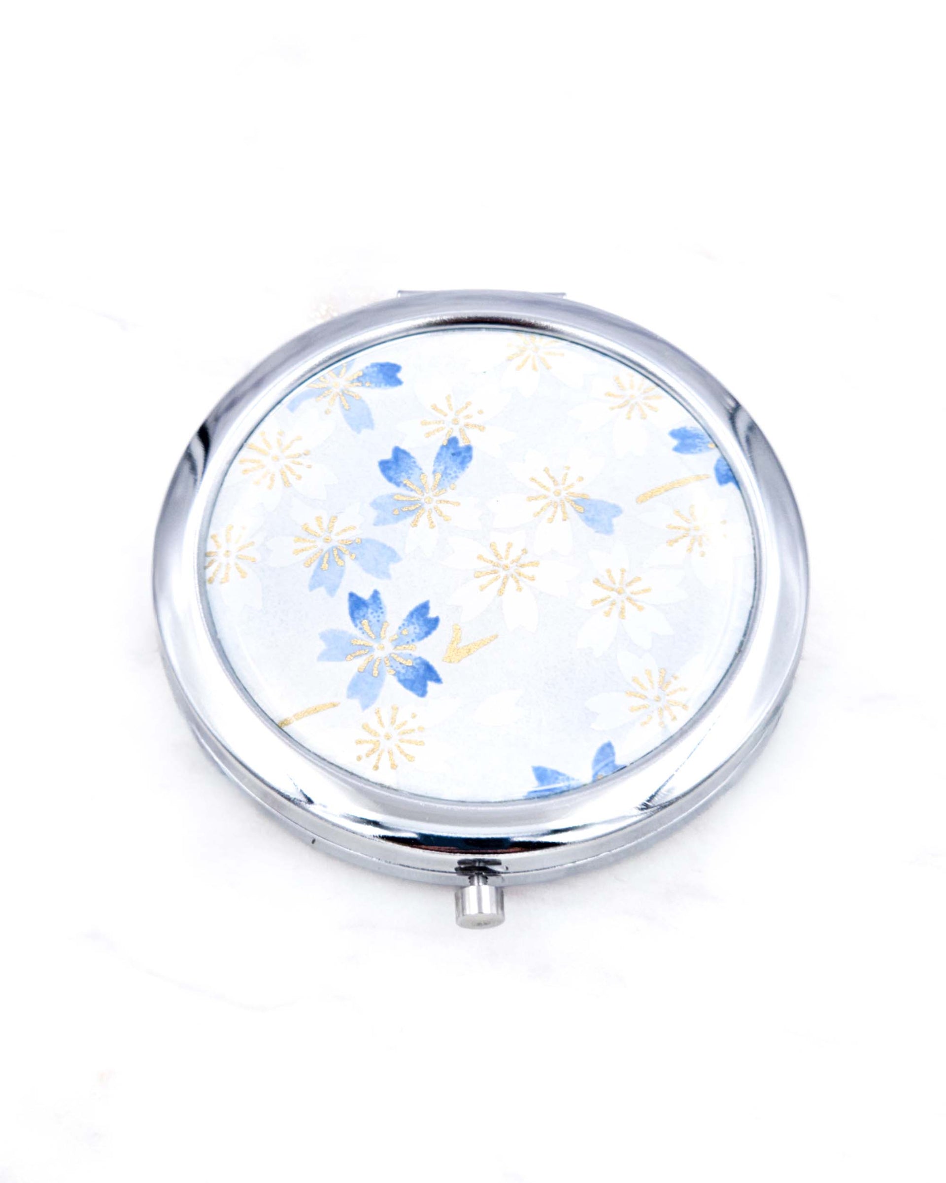 Silver metal compact mirror featuring white and blue cherry blossoms on a light white and blue background with metallic gold accents.