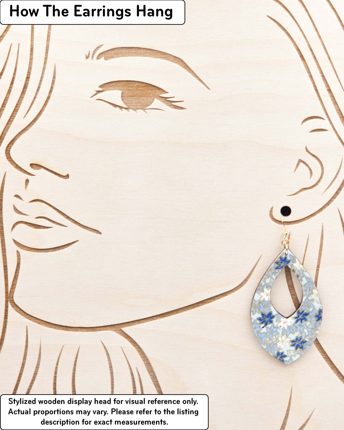 Large wooden hollow pointed teardrop shaped earrings featuring small blue and white momiji (maple leaves) on a light blue background with metallic gold details, displayed on a stylized wooden head to demonstrate how the earring hangs when worn. Display is not to scale.