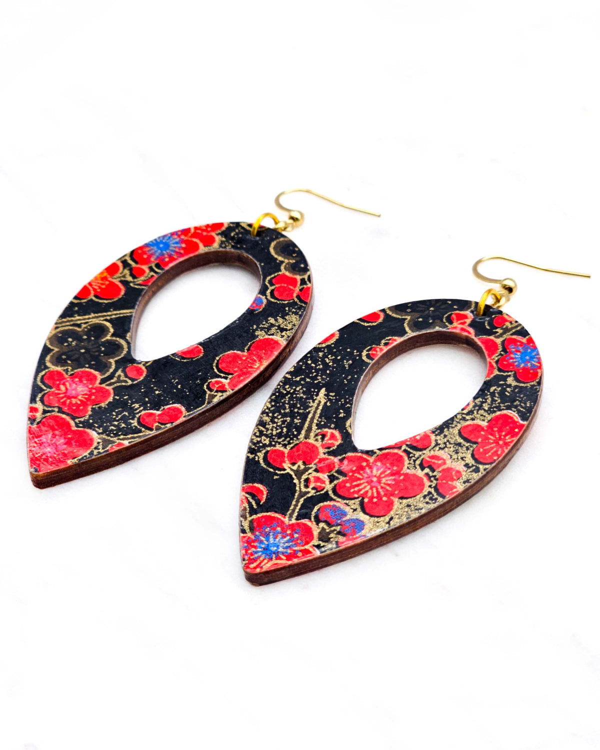 Large wooden hollow reverse teardrop earrings featuring red plum blossoms with a little bit of blue on a black background with metallic gold details