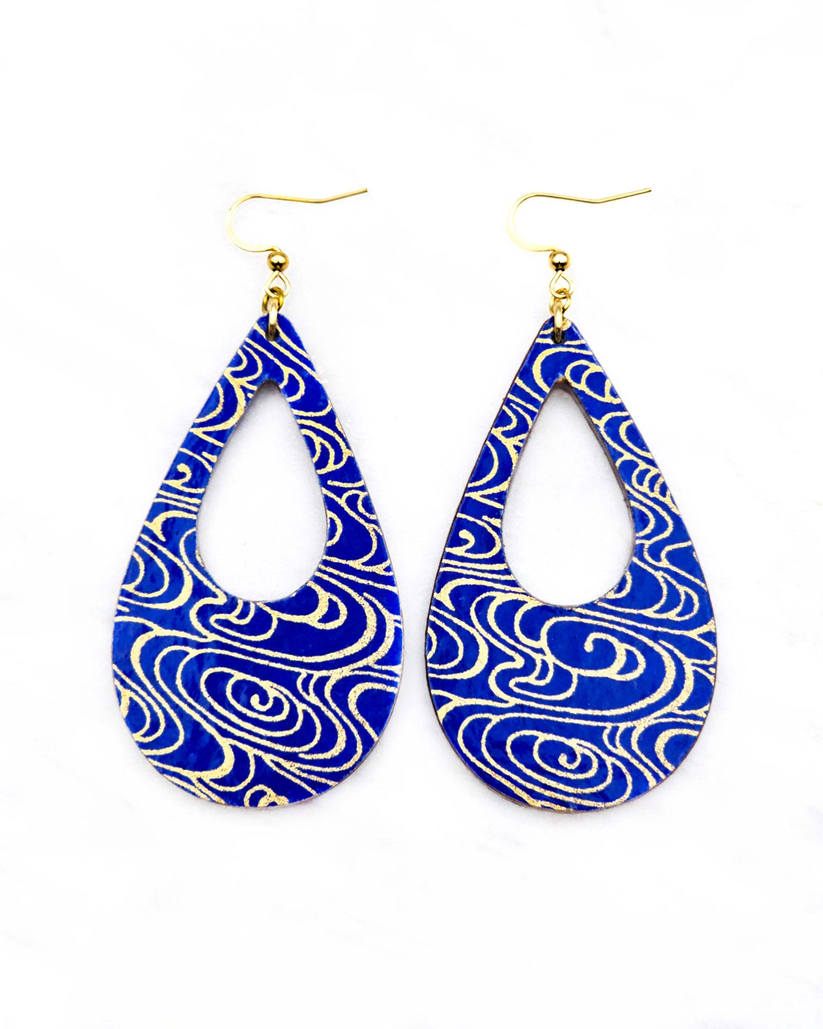 Large wooden hollow teardrop earrings featuring metallic gold water ripples on a dark blue background.