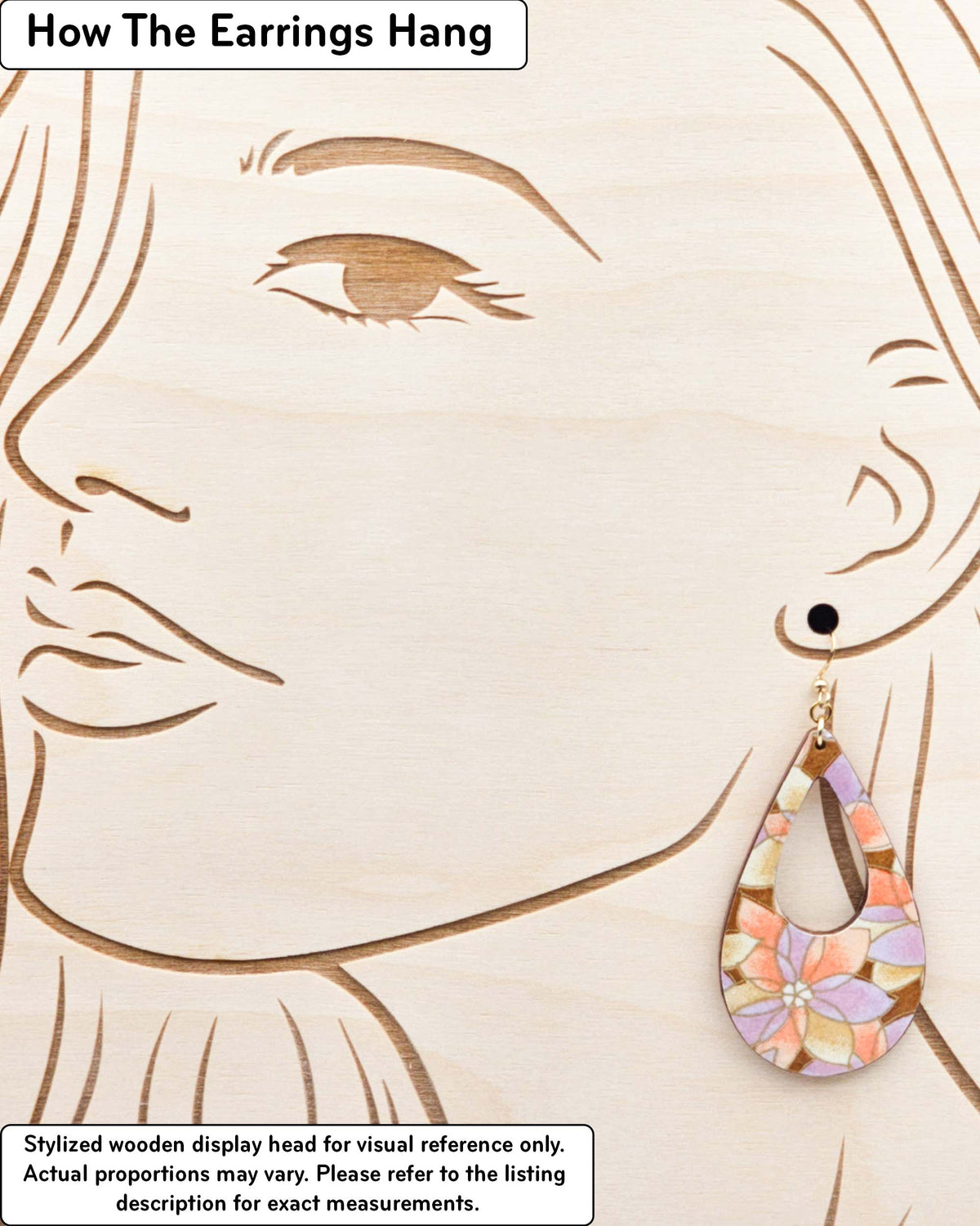 Large wooden hollow teardrop earrings featuring orange, brown, and light purple lotuses on a brown background with metallic gold details, displayed on a stylized wooden head to demonstrate how the earring hangs when worn. Display is not to scale.