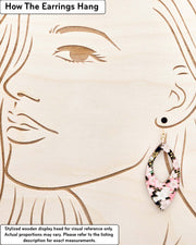 Large wooden hollow pointed oval shaped earrings featuring pink and white cherry blossoms on a black background with metallic gold details, displayed on a stylized wooden head to demonstrate how the earring hangs when worn. Display is not to scale.