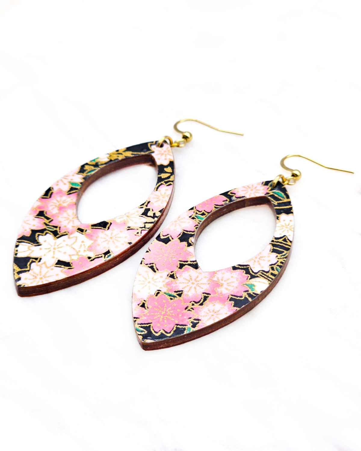 Large wooden hollow pointed oval shaped earrings featuring pink and white cherry blossoms on a black background with metallic gold details.