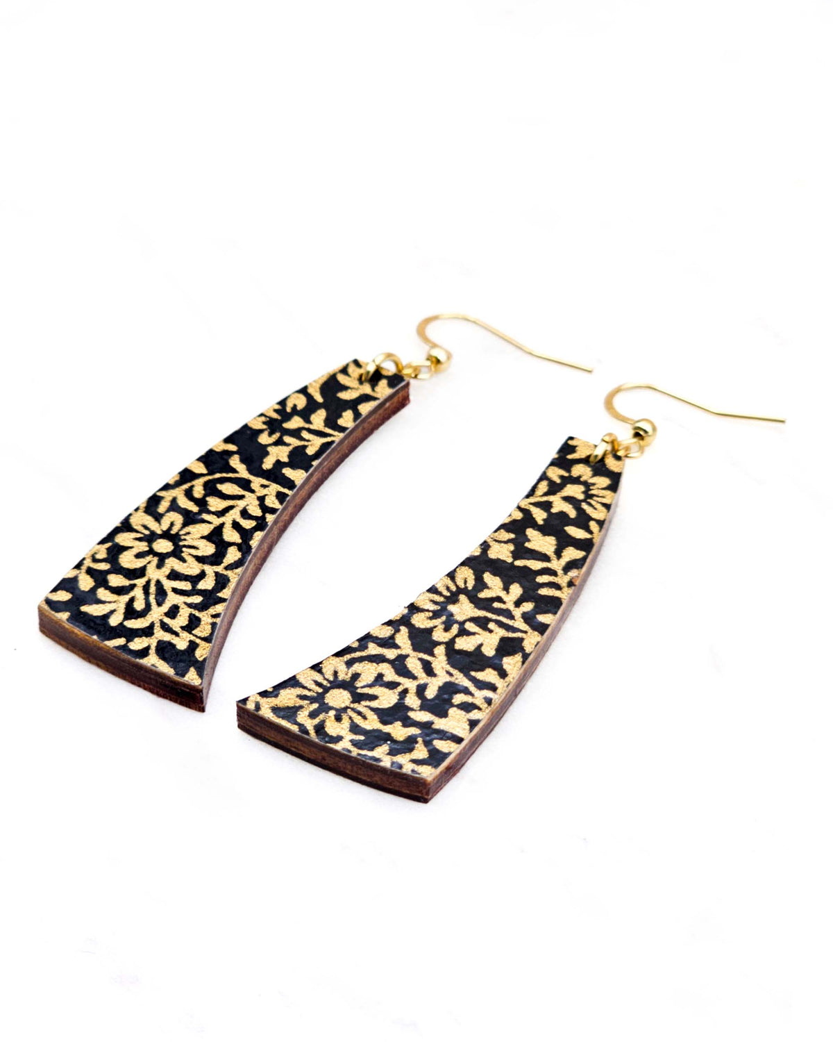 Medium wooden curved bar shaped earrings featuring a metallic gold floral motif on a black background.