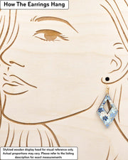 Medium wooden hollow diamond shaped earrings featuring small blue and white momiji (maple leaves) on a light blue background with metallic gold details, displayed on a stylized wooden head to demonstrate how the earring hangs when worn. Display is not to scale.