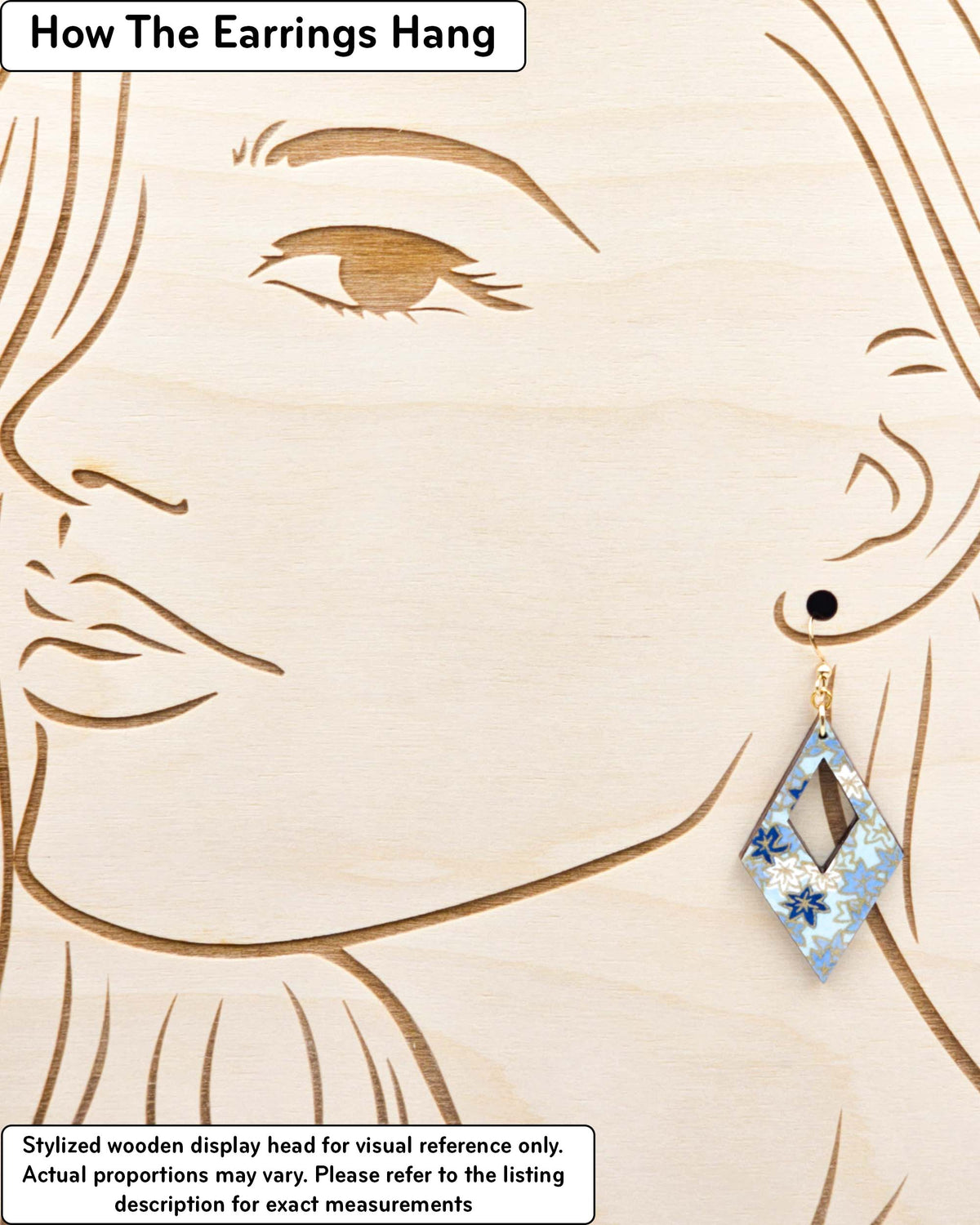 Medium wooden hollow diamond shaped earrings featuring small blue and white momiji (maple leaves) on a light blue background with metallic gold details, displayed on a stylized wooden head to demonstrate how the earring hangs when worn. Display is not to scale.