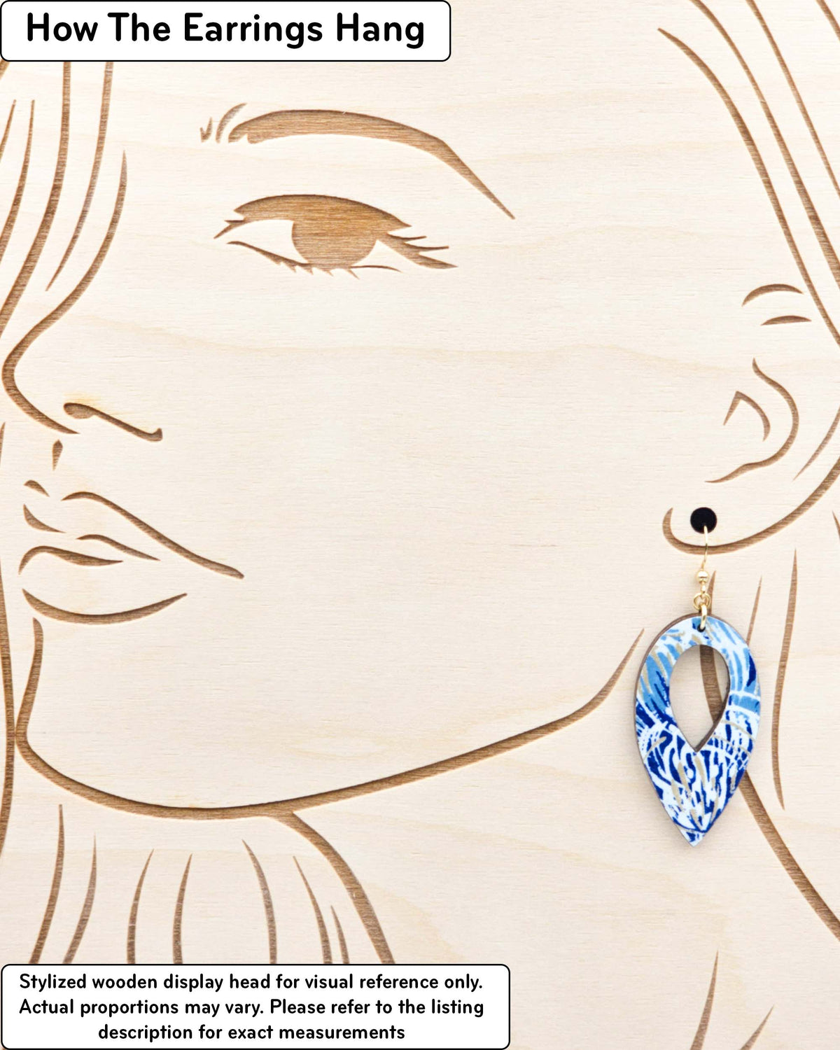 Medium wooden hollow reverse teardrop shaped earrings featuring blue chrysanthemums on a dark blue background with metallic gold details, displayed on a stylized wooden head to demonstrate how the earring hangs when worn. Display is not to scale.