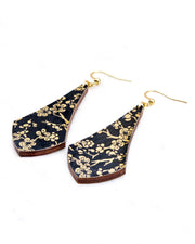 Medium wooden long anchor shaped earrings featuring small metallic gold plum blossom branches on a black background.