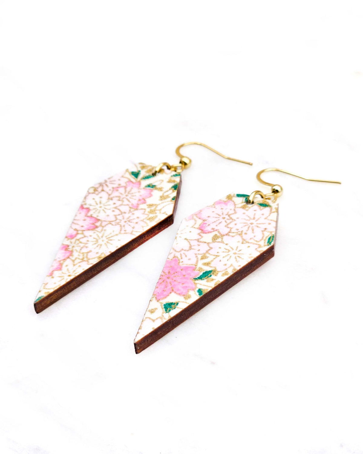 Medium wooden long diamond shaped earrings featuring light pink cherry blossoms a light cream background with metallic gold details.