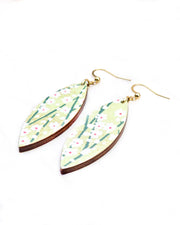 Medium wooden thin pointed oval shaped earrings featuring small white flower bushes with green stems over a yellow green background with metallic gold details.