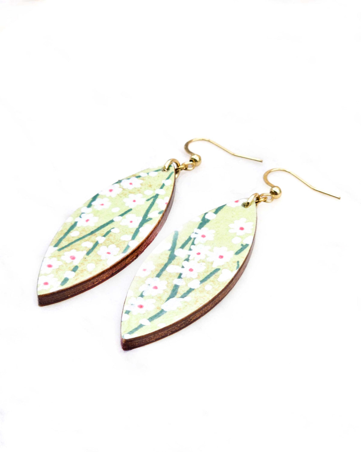 Medium wooden thin pointed oval shaped earrings featuring small white flower bushes with green stems over a yellow green background with metallic gold details.