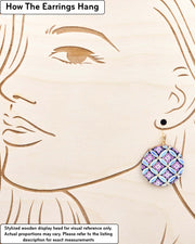 Medium wooden circle shaped earrings featuring a blue shippo design with purple hanabishi in the center with metallic gold details, displayed on a stylized wooden head to demonstrate how the earring hangs when worn. Display is not to scale.