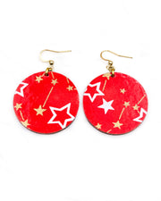 Medium wooden circle shaped earrings featuring white assorted stars and smaller metallic gold stars and constellations on a red background.
