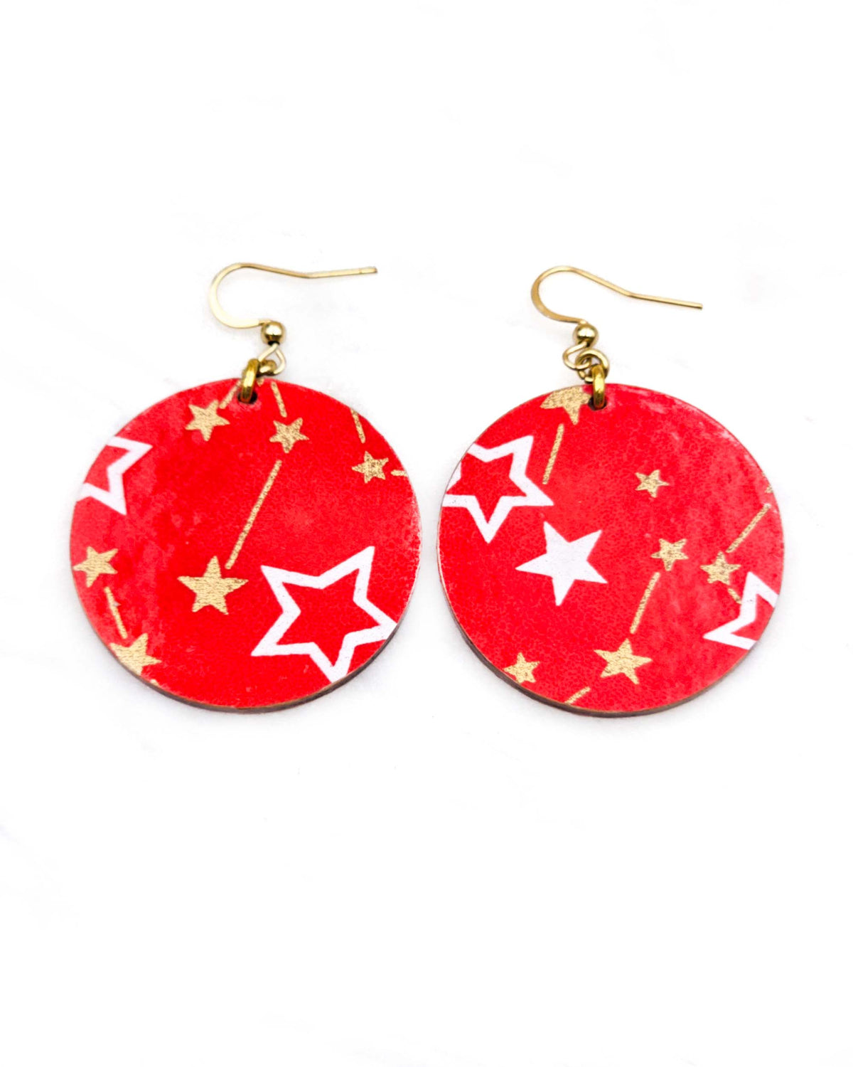 Medium wooden circle shaped earrings featuring white assorted stars and smaller metallic gold stars and constellations on a red background.