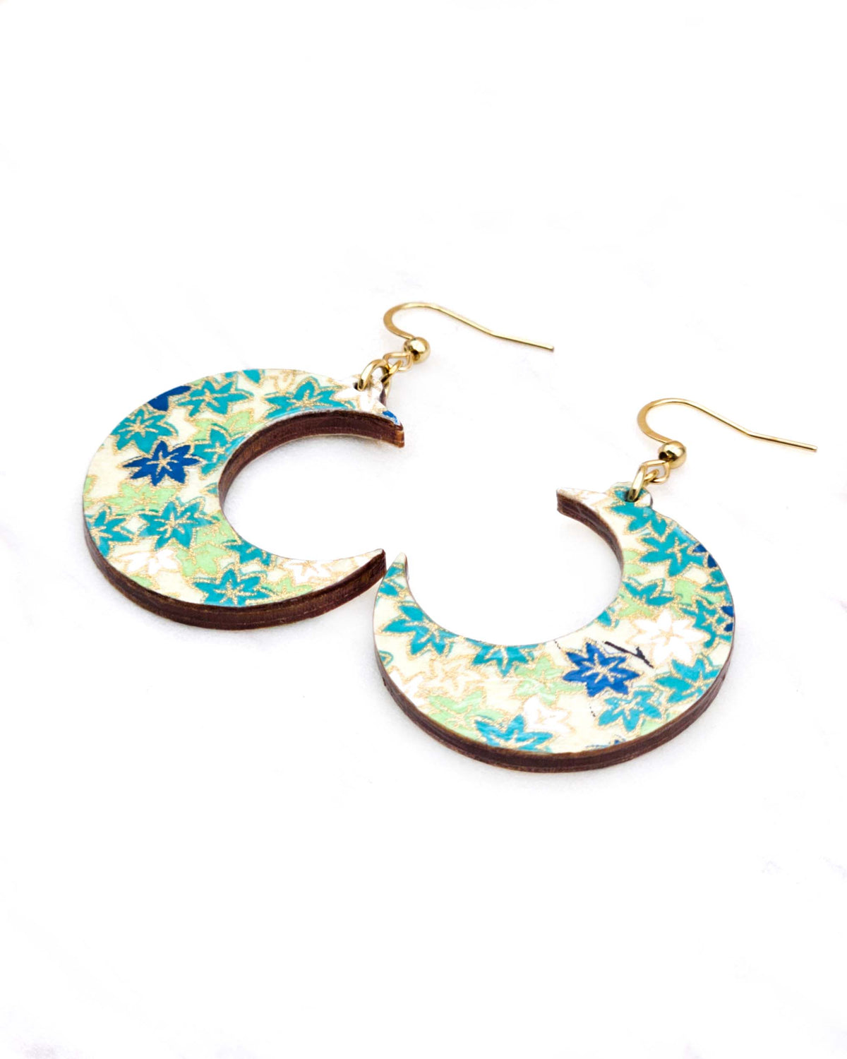 Medium wooden crescent moon shaped earrings featuring small green and white momiji (maple leaves) on a light green background with metallic gold details.