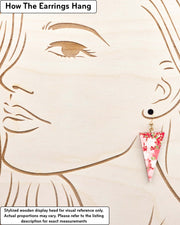 Medium wooden downward triangle shaped earrings featuring red and white cherry blossoms on a red background with metallic gold details, displayed on a stylized wooden head to demonstrate how the earring hangs when worn. Display is not to scale.