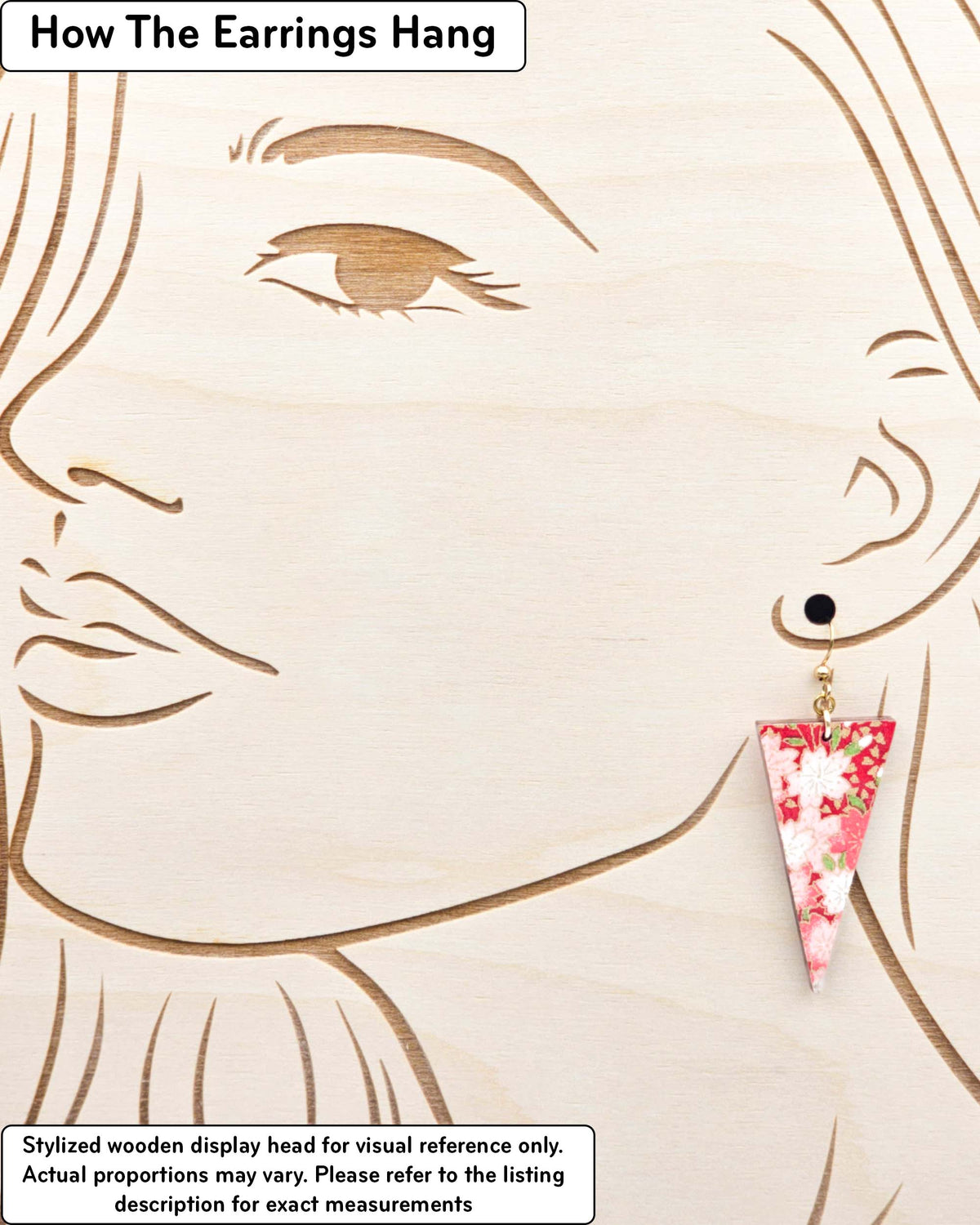 Medium wooden downward triangle shaped earrings featuring red and white cherry blossoms on a red background with metallic gold details, displayed on a stylized wooden head to demonstrate how the earring hangs when worn. Display is not to scale.