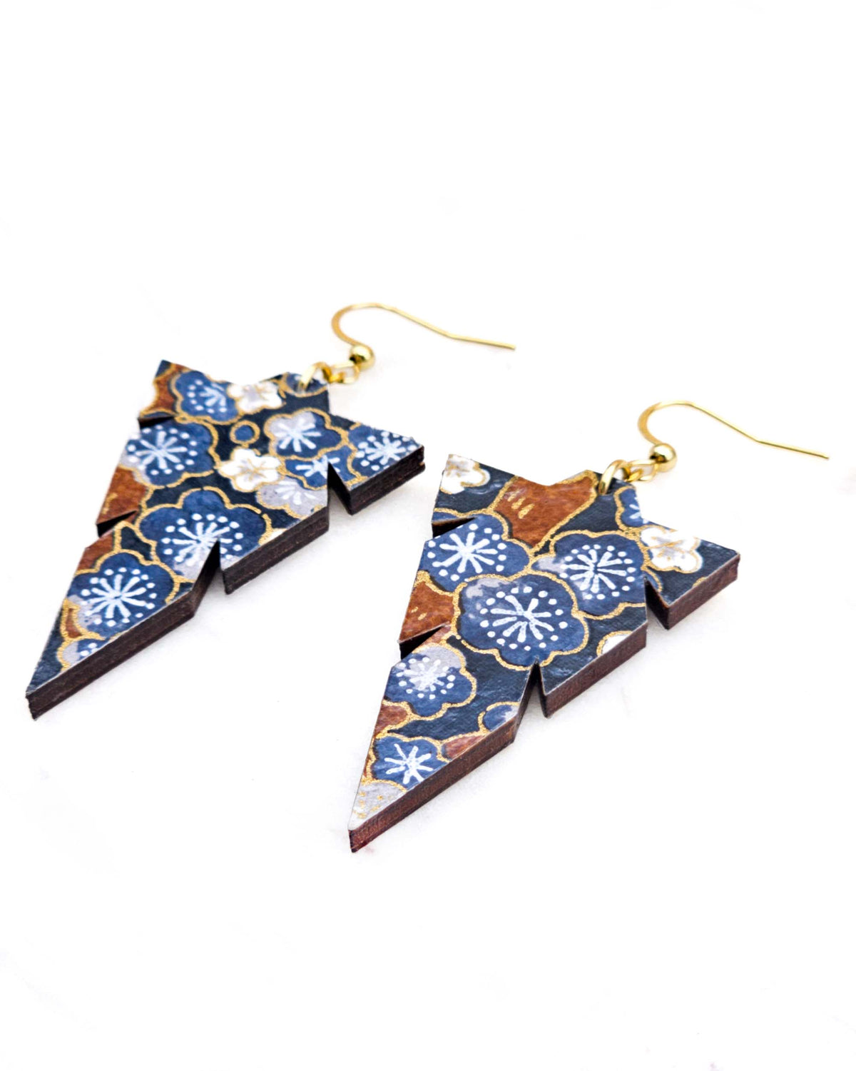 Medium wooden notched triangle shaped earrings featuring blue and gray plum blossoms with brown branches on a dark blue background with metallic gold details.