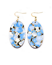 Medium wooden oval shaped earrings featuring blue plum blossoms on a black background with metallic gold details.