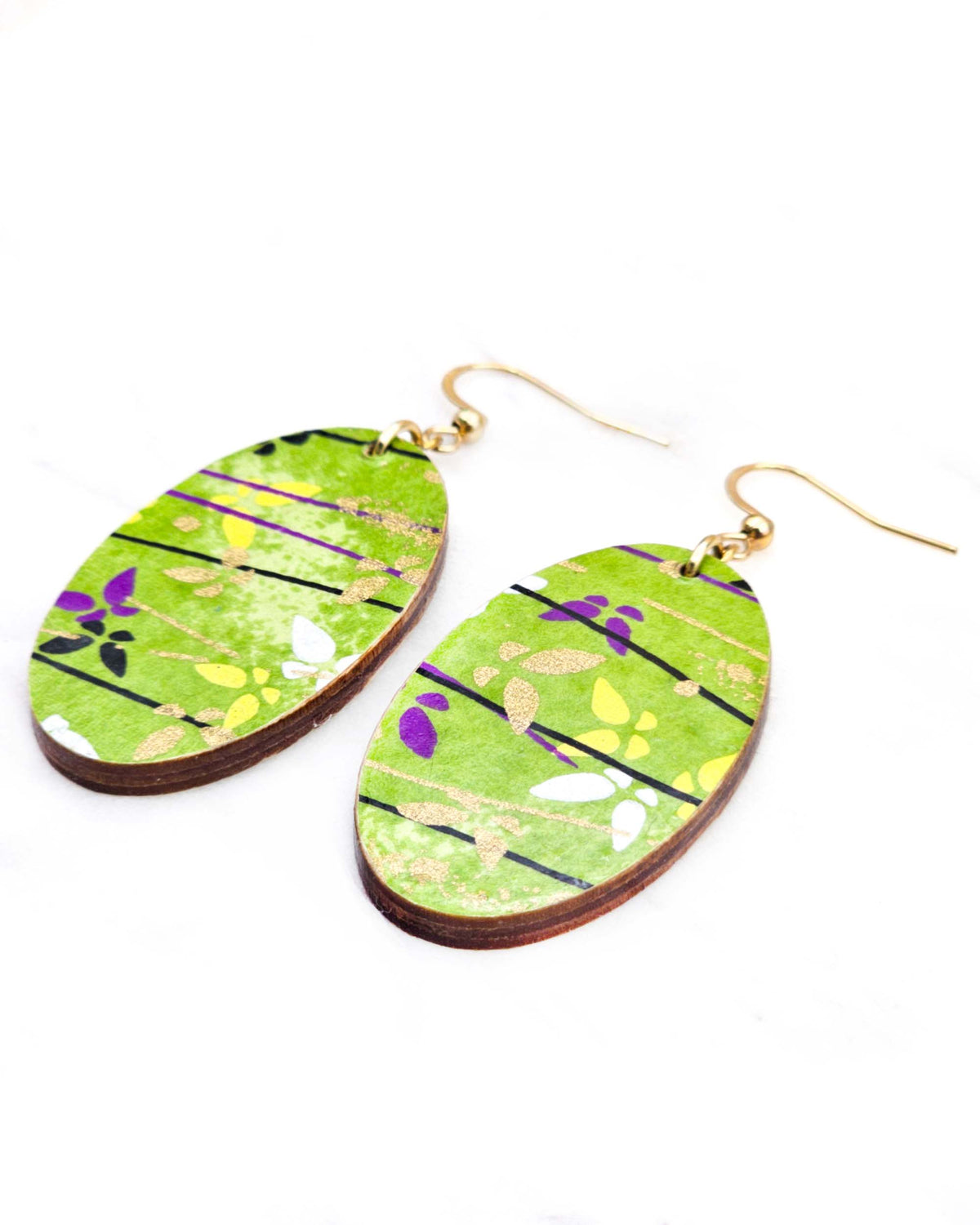 Medium wooden oval shaped earrings featuring small white cherry blossoms and cherry blossom outlines on a red background.