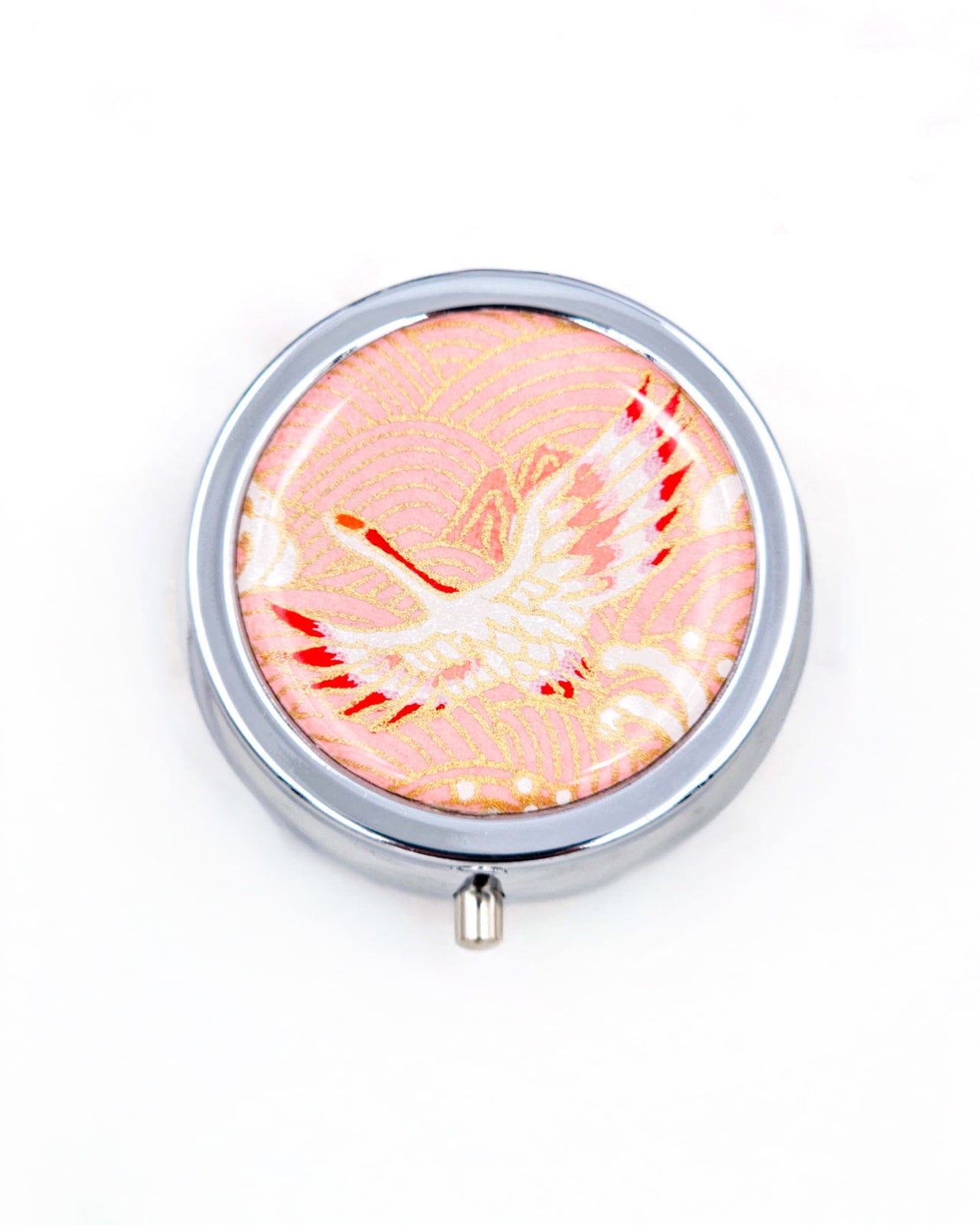 Silver metal pill box featuring a flying crane on a pink background with metallic gold accent.