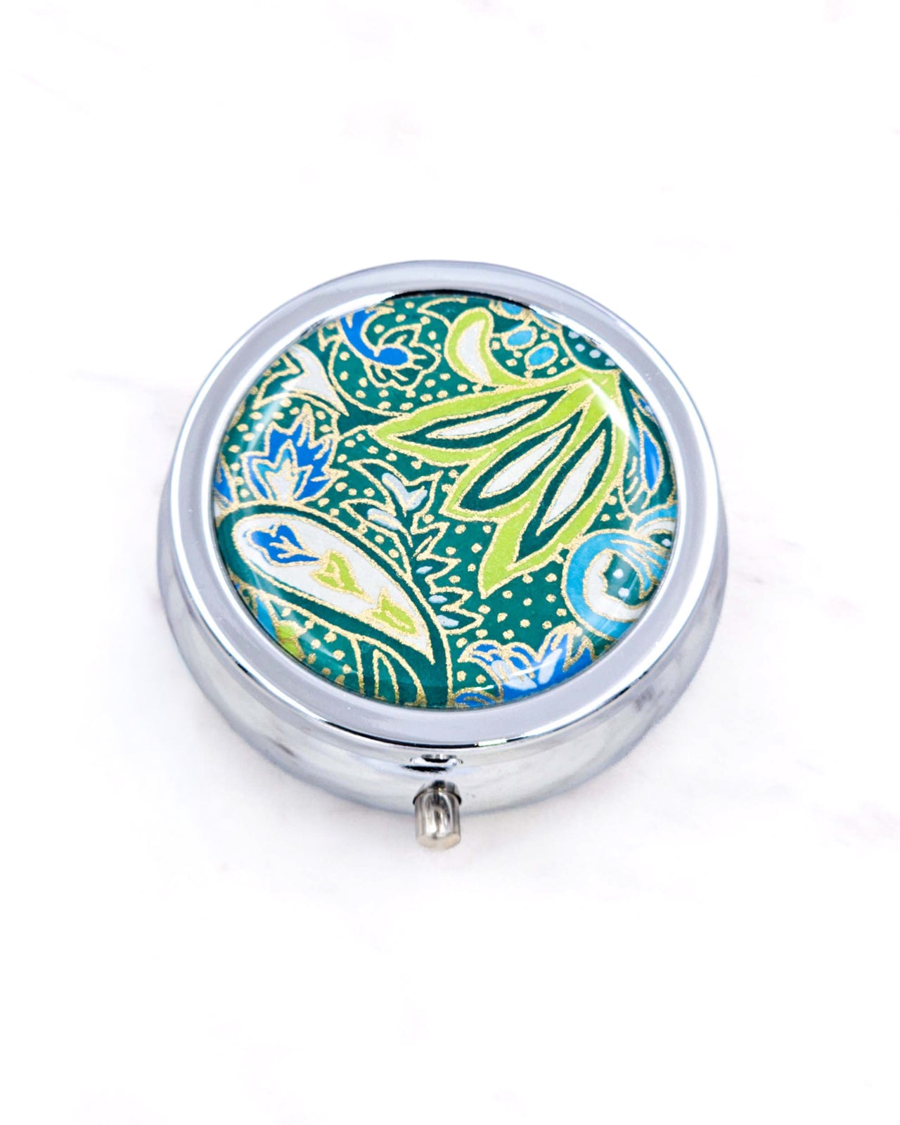 Silver metal pill box featuring a green and blue paisley design with metallic gold accents.