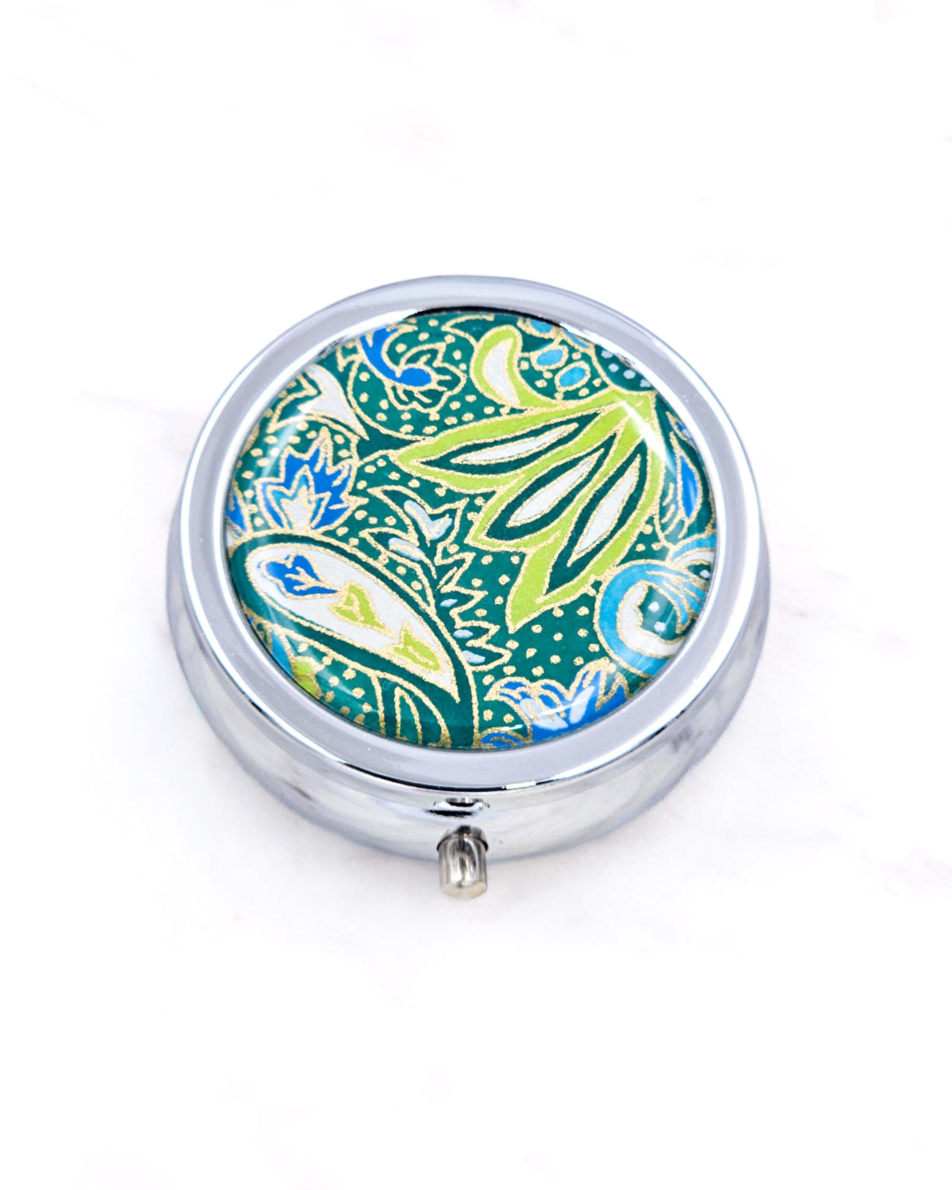 Silver metal pill box featuring a green and blue paisley design with metallic gold accents.