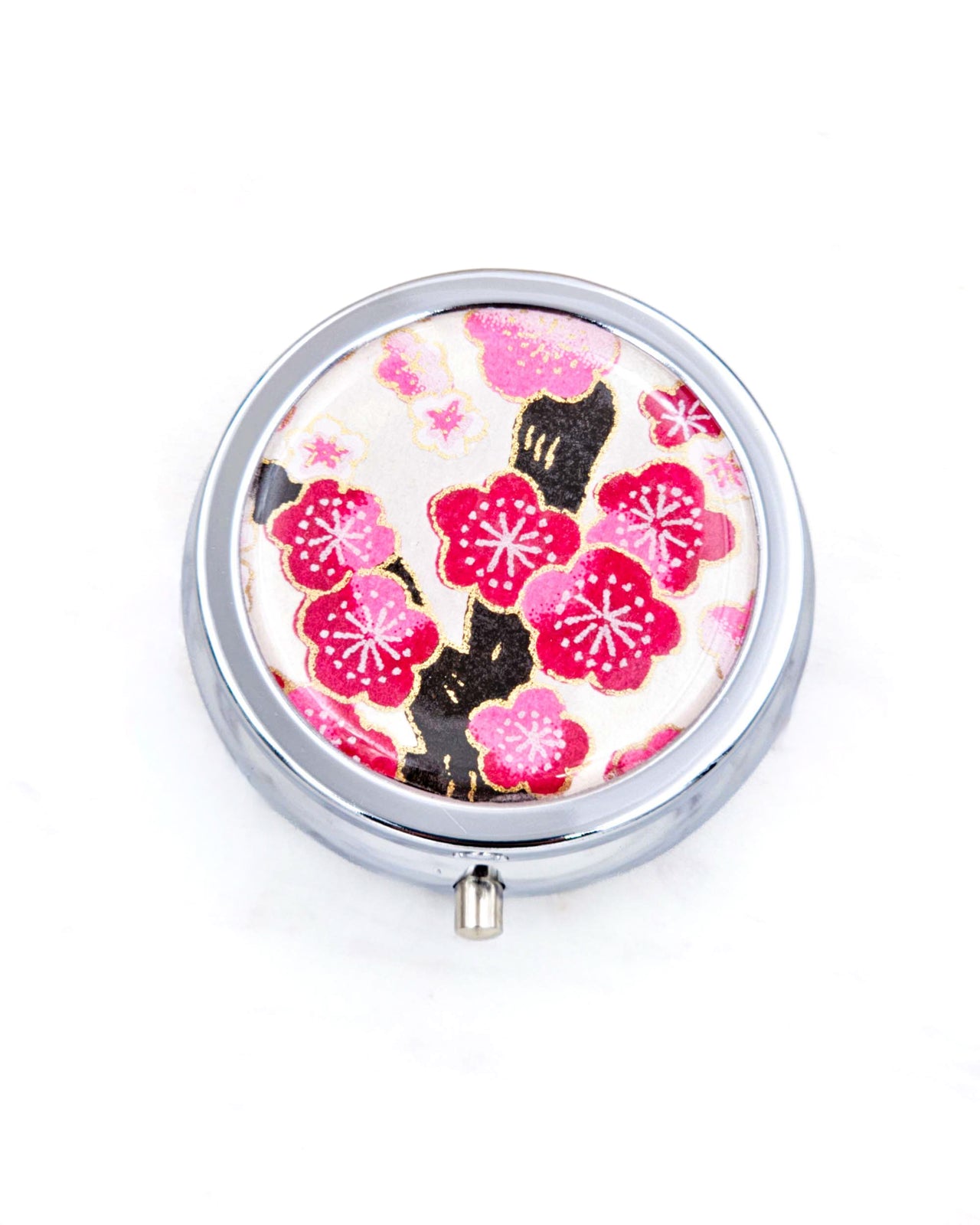 Silver metal pill box featuring a pink plum blossom tree on a white background with metallic gold accents.