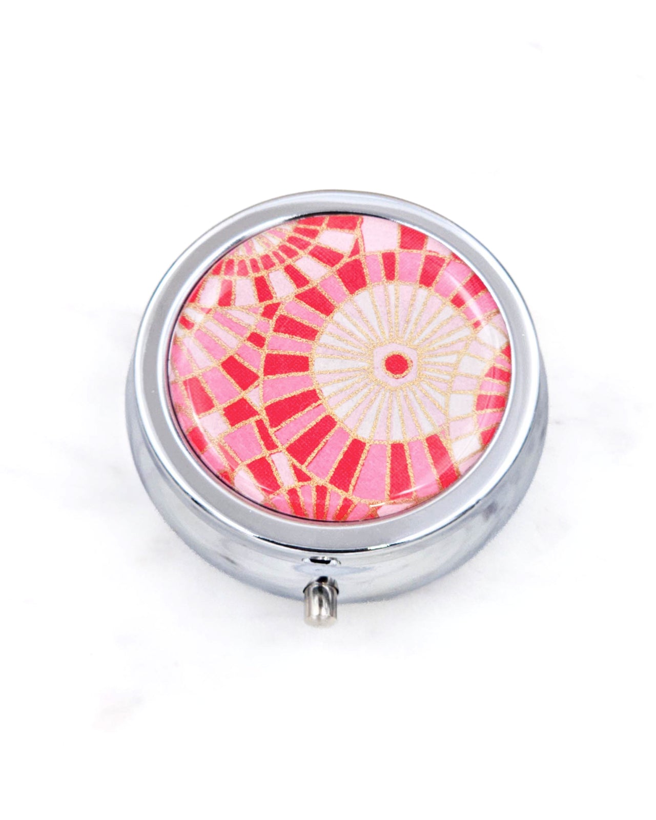 Silver metal pill box featuring pink and white abstract parasols with metallic gold accents.