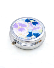 Silver metal pill box featuring purple and blue pansies background with metallic gold accents.