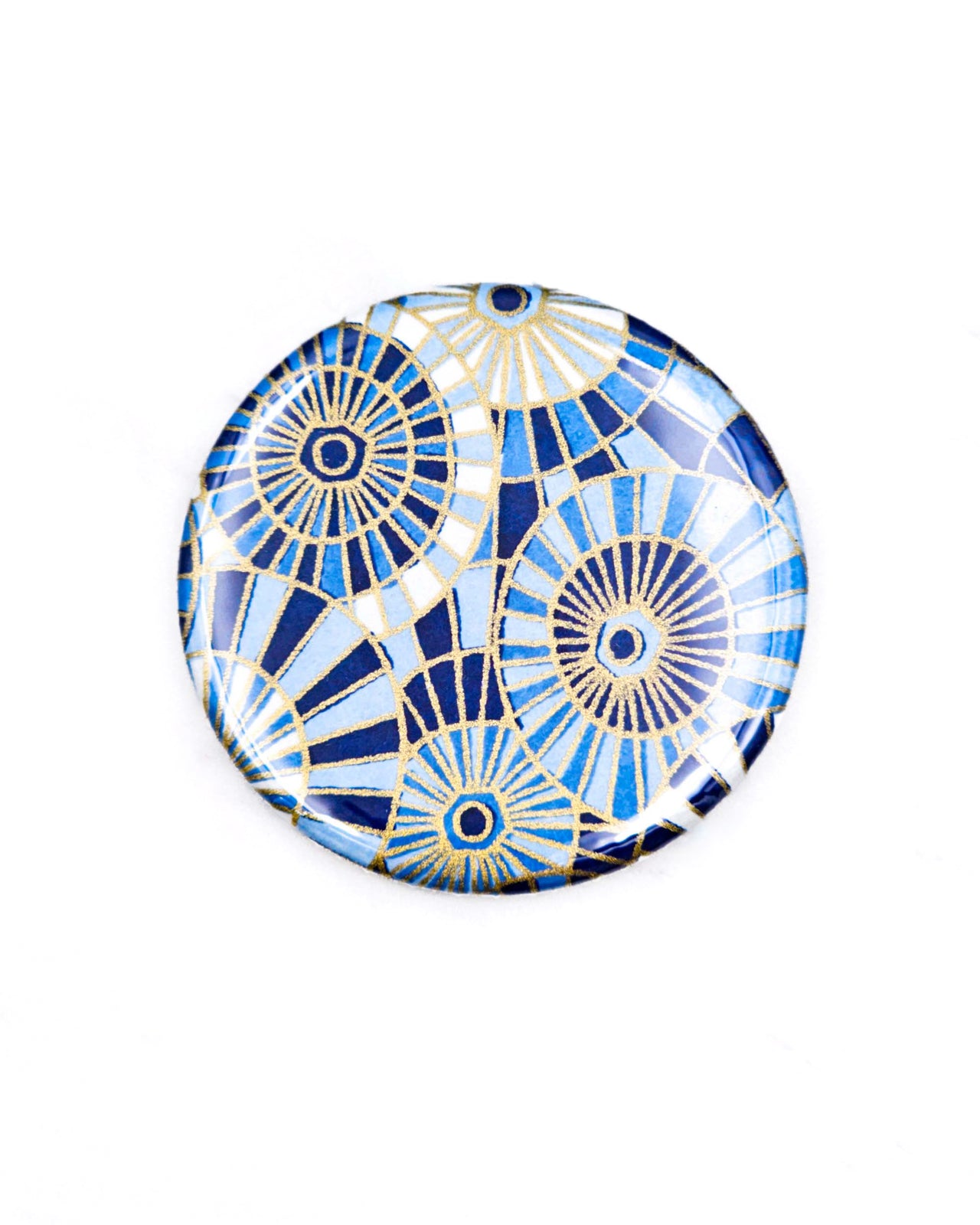 Round pocket mirror featuring blue and white abstract parasols with metallic gold accents.