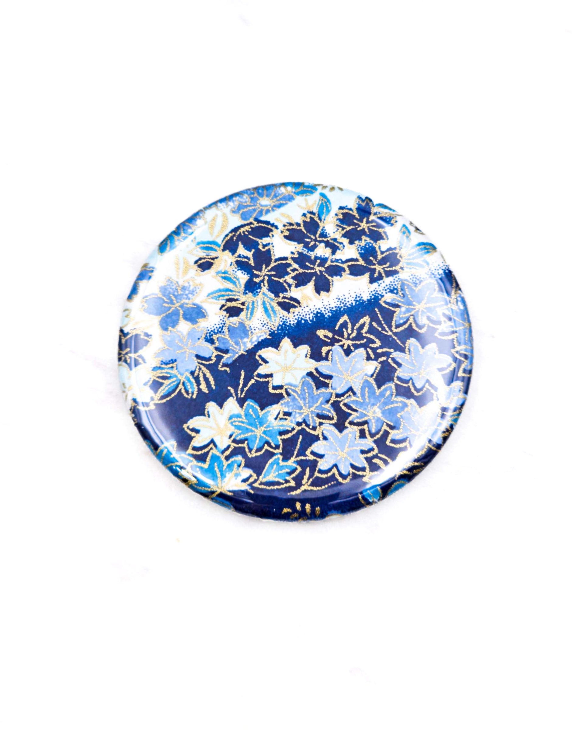 Round pocket mirror featuring blue and white cherry blossoms and maple leaves on a blue and white background with metallic gold accents.