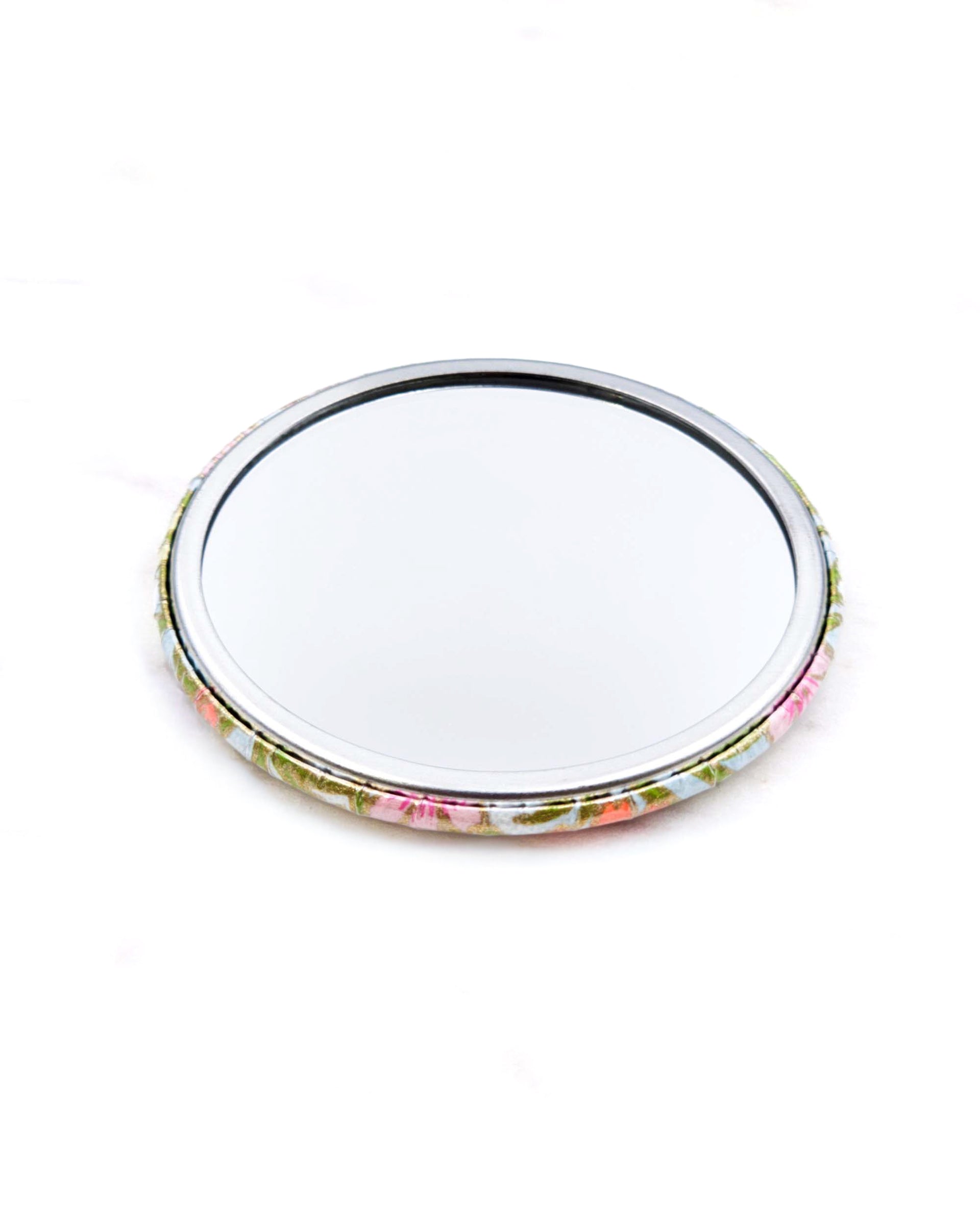 Round pocket mirror featuring pink and orange flower stalks on a light blue background with metallic gold accents.