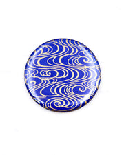 Round pocket mirror featuring metallic gold water ripples on a dark blue background.
