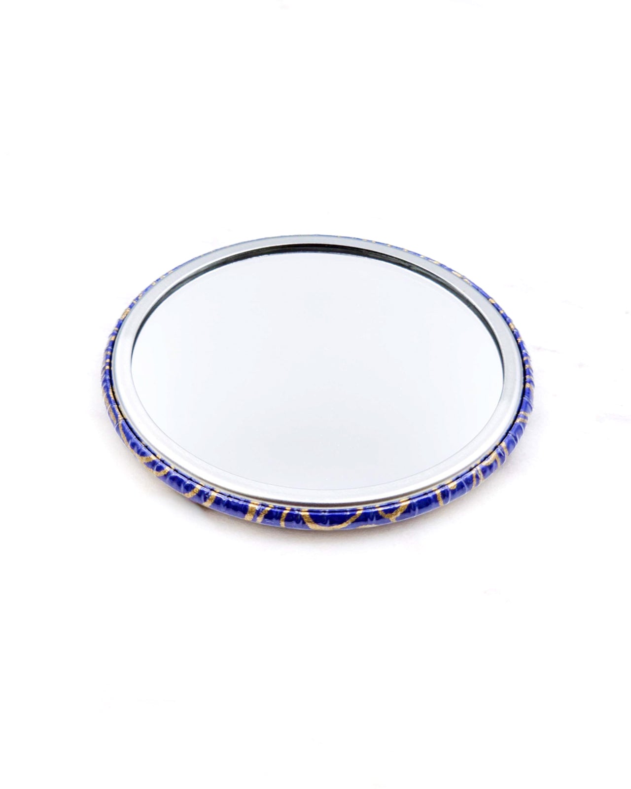Round pocket mirror featuring metallic gold water ripples on a dark blue background.