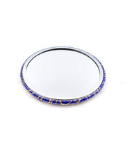 Round pocket mirror featuring metallic gold water ripples on a dark blue background.