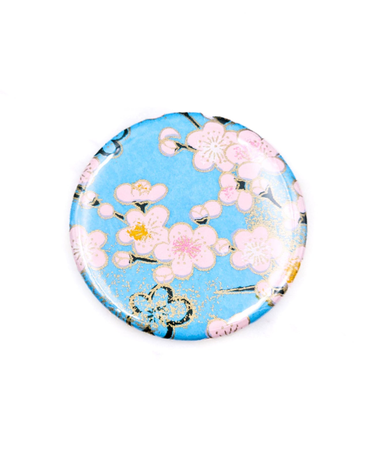 Round pocket mirror featuring a pink plum blossoms on a light blue background with metallic gold accents.