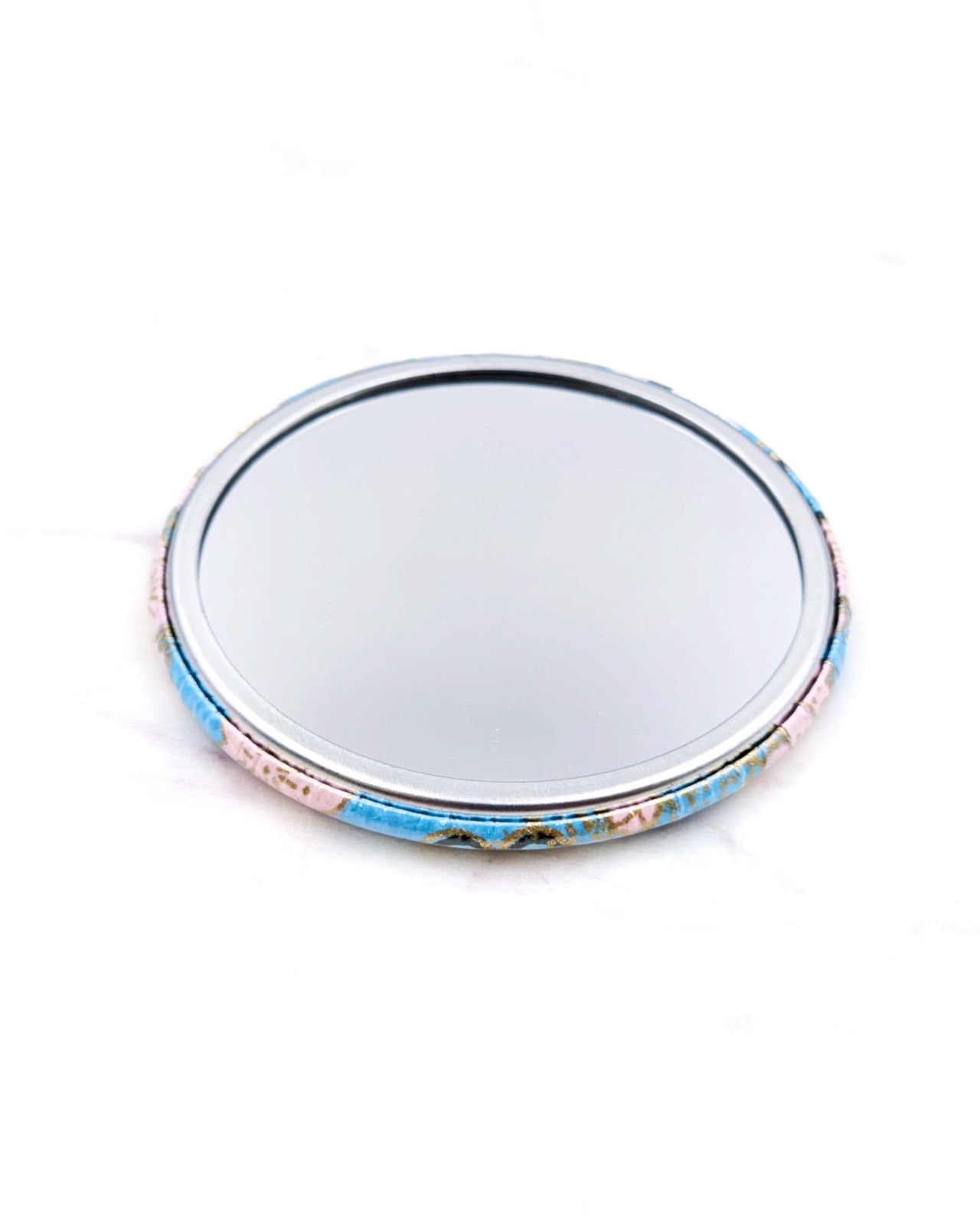 Round pocket mirror featuring a pink plum blossoms on a light blue background with metallic gold accents.