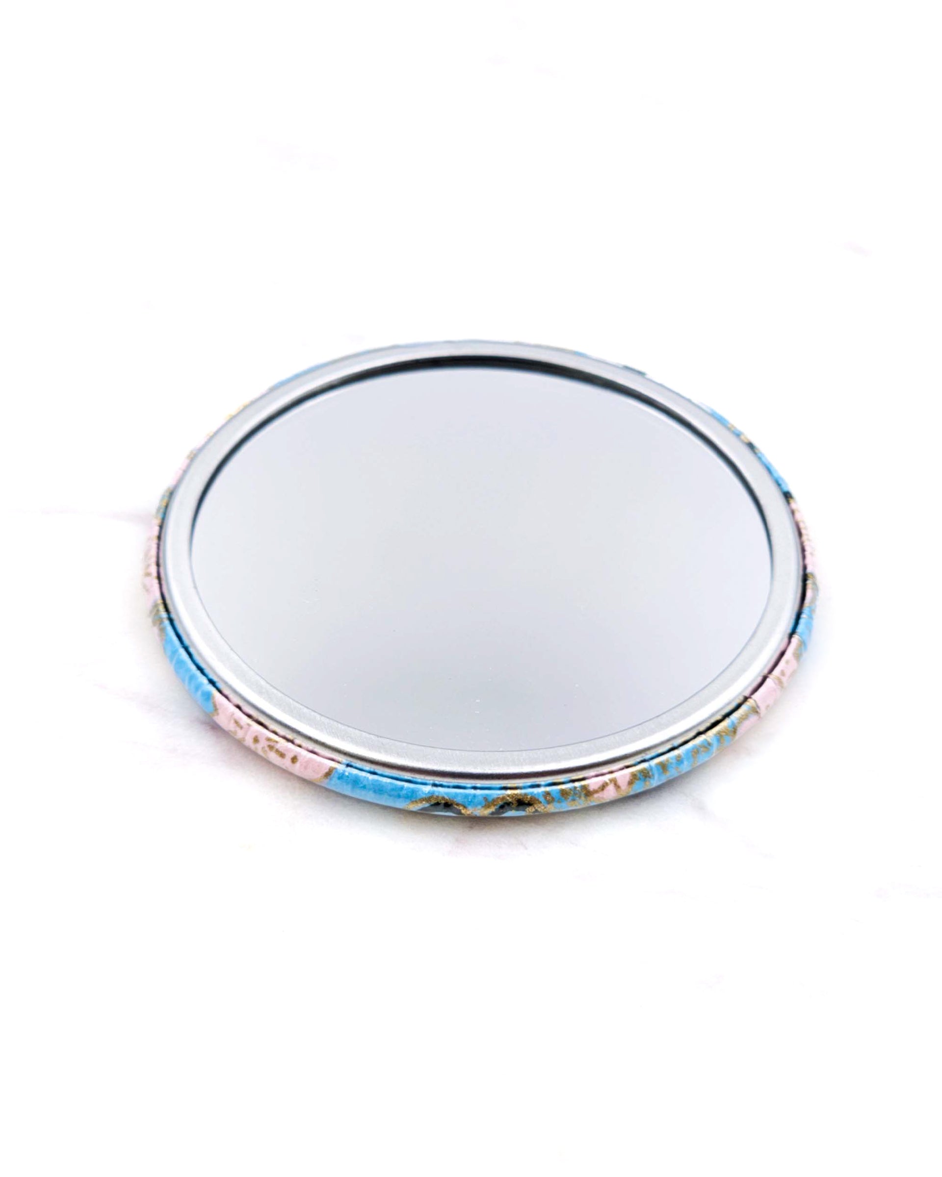 Round pocket mirror featuring a pink plum blossoms on a light blue background with metallic gold accents.