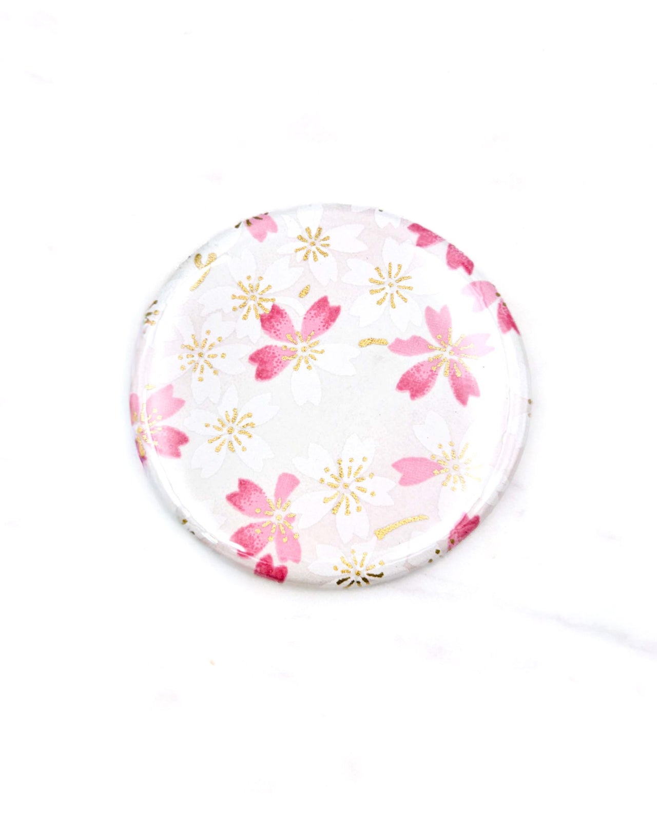Round pocket mirror featuring pink and white cherry blossoms on a white background with metallic gold accents.